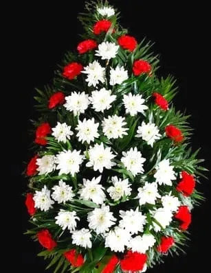 Coroana funerara cu flori albe în centru, înconjurate de flori roșii și frunze verzi