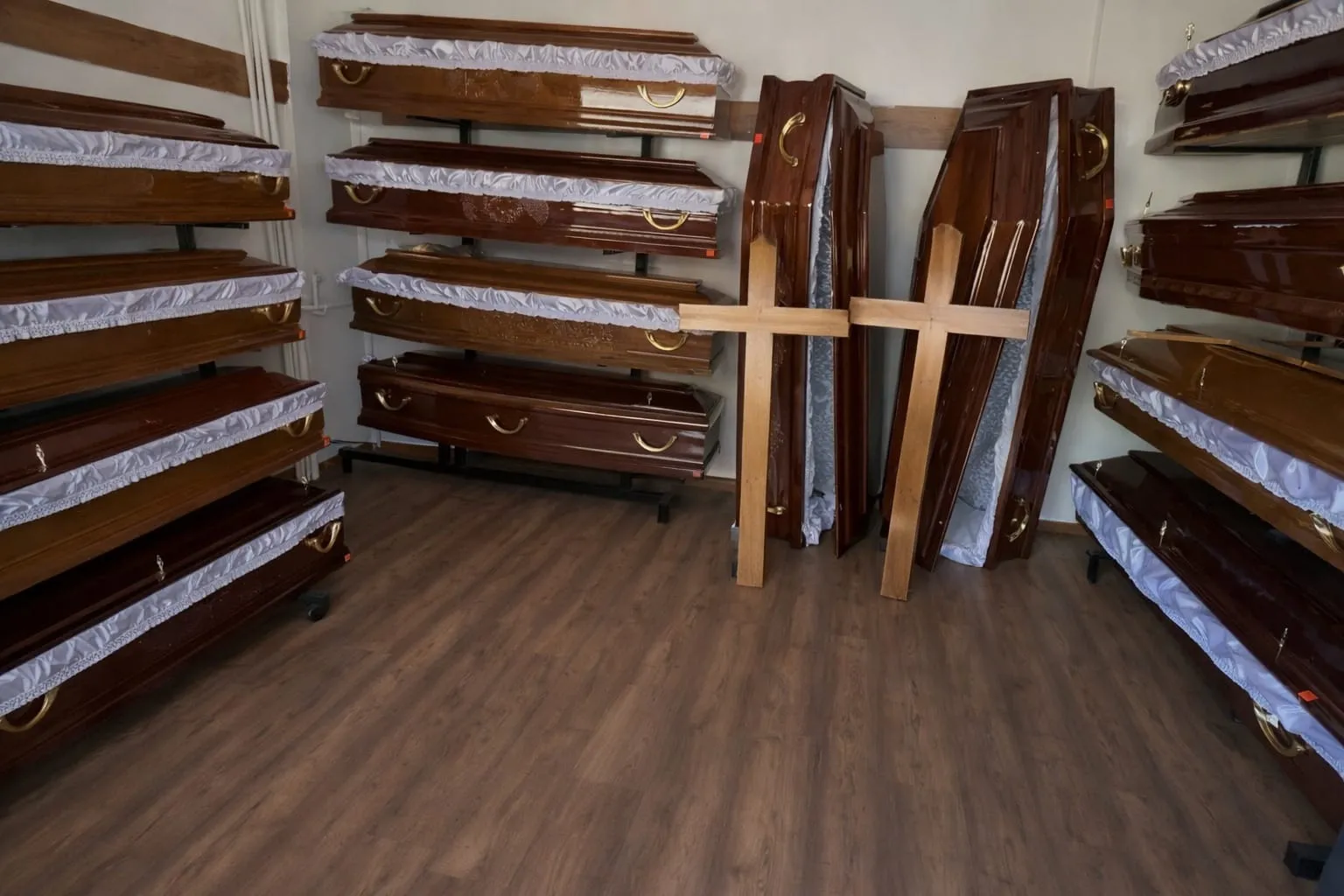 Două cruci de lemn sunt sprijinite în picioare printre sicrie sugerând un magazin servicii funerare